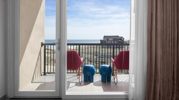 Un balcone con vista sulla spiaggia e una casa all'orizzonte.