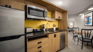 Una cucina moderna con frigorifero, forno a microonde, lavello e pensili in legno.