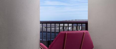 A balcony with a view of the sea, a red chair, and a blue exercise ball.
