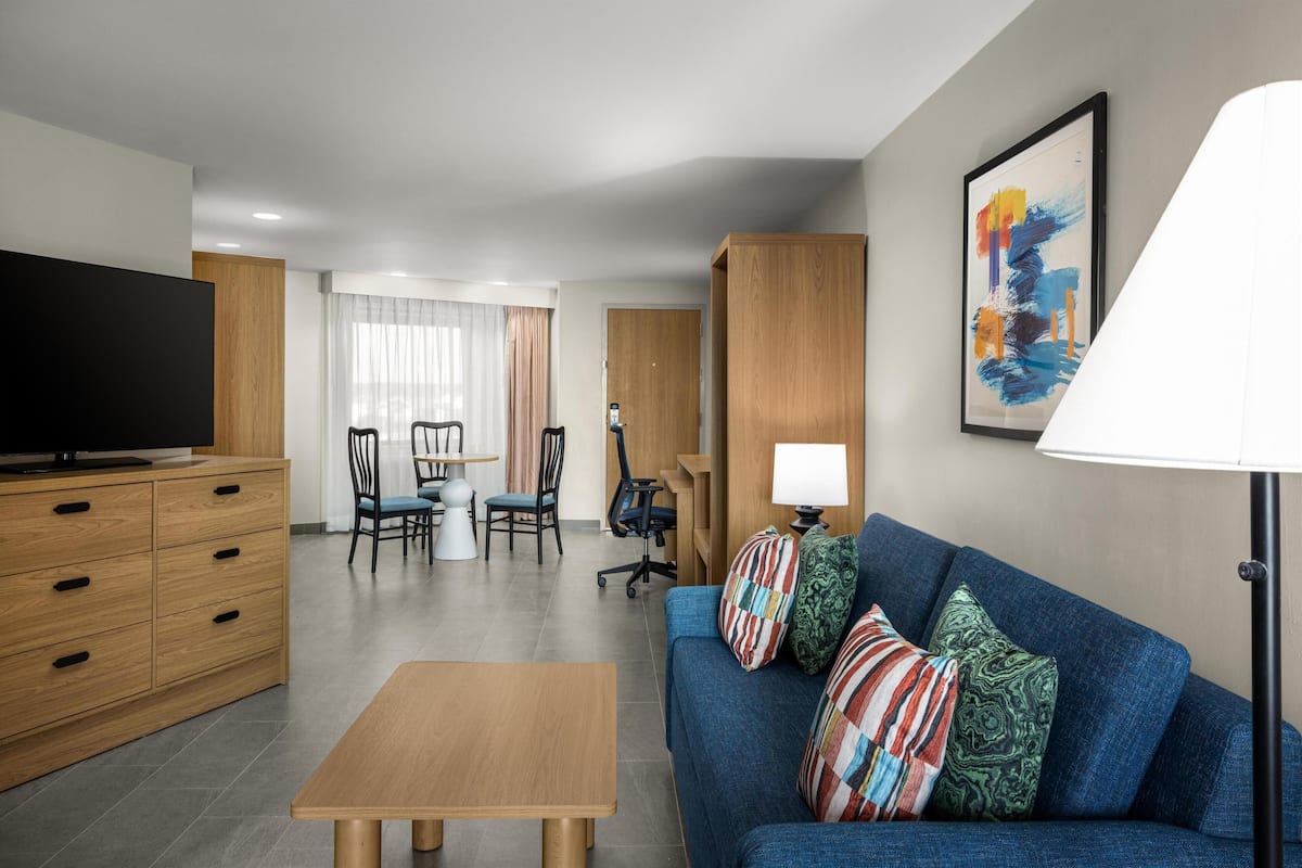 A modern living room with a sofa, a television, a dining table, and a lamp.