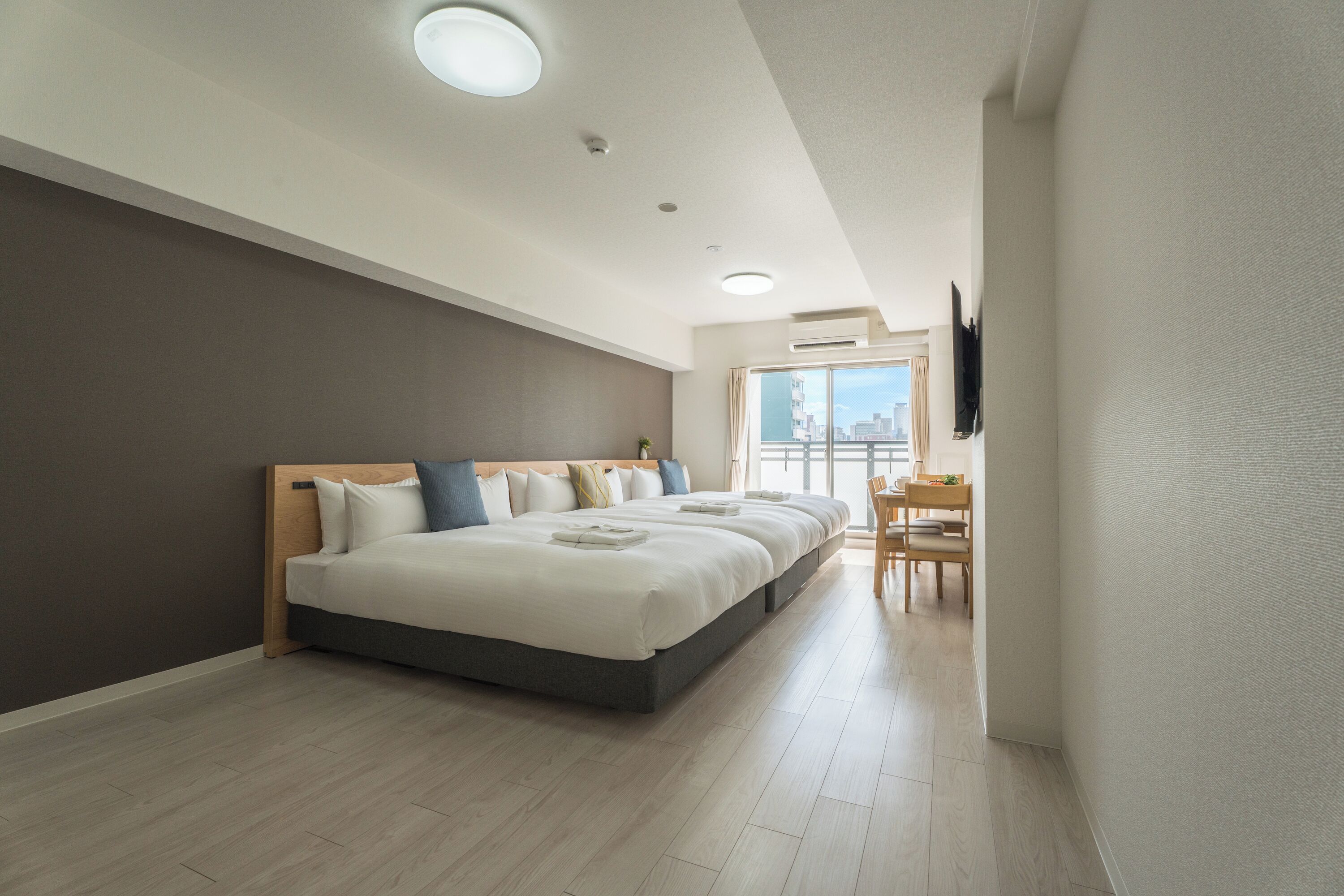 A modern hotel room with a large bed, a desk, and a city view.