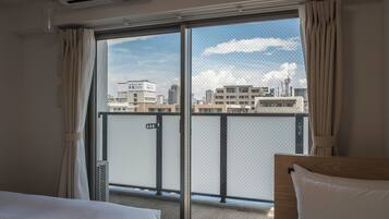 Ett hotellrum med en stor skjutdörr i glas som leder ut till en balkong med utsikt över staden.