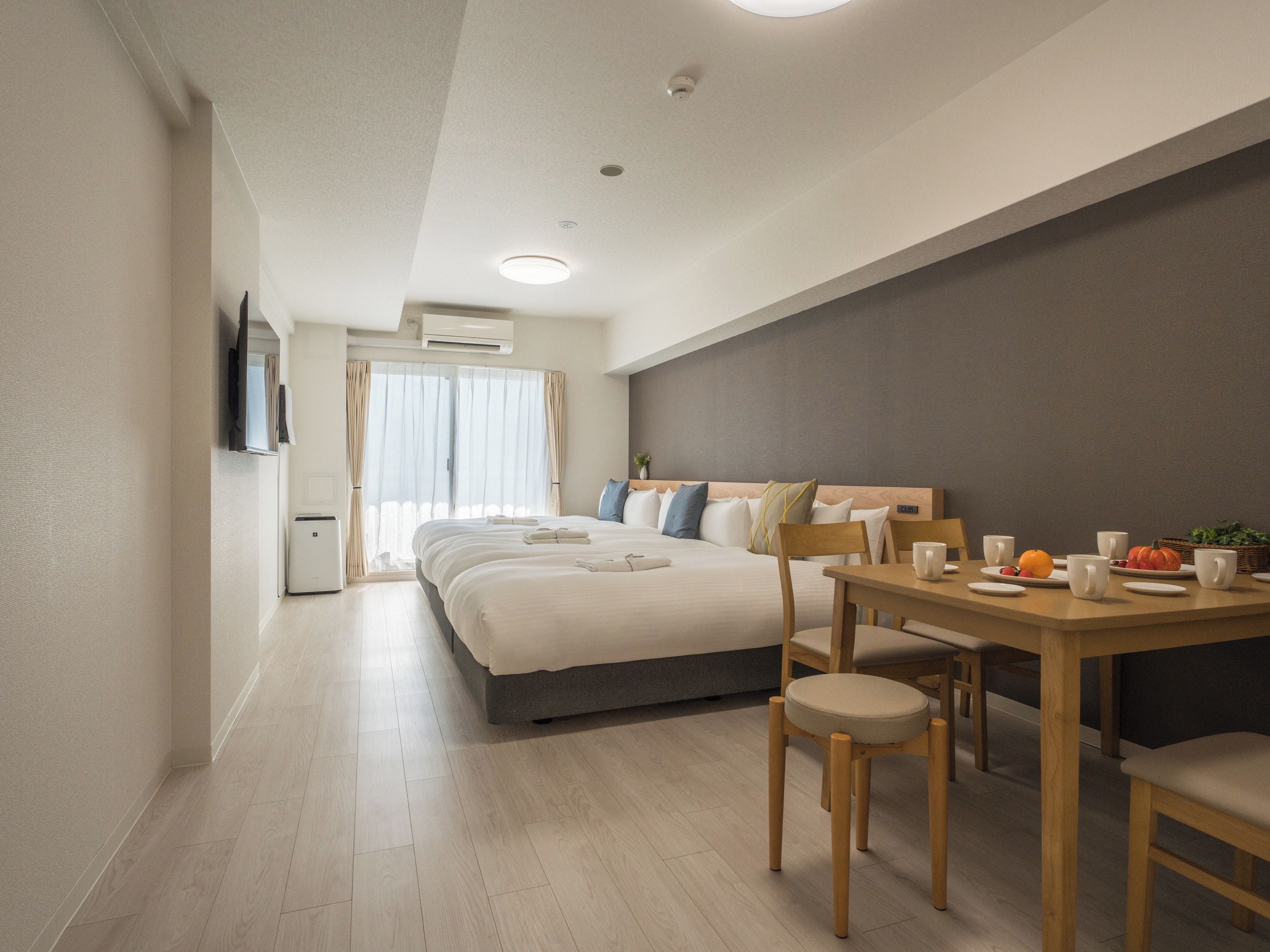 Een moderne hotelkamer met een groot bed, een eettafel met stoelen en een aan de muur bevestigde televisie.