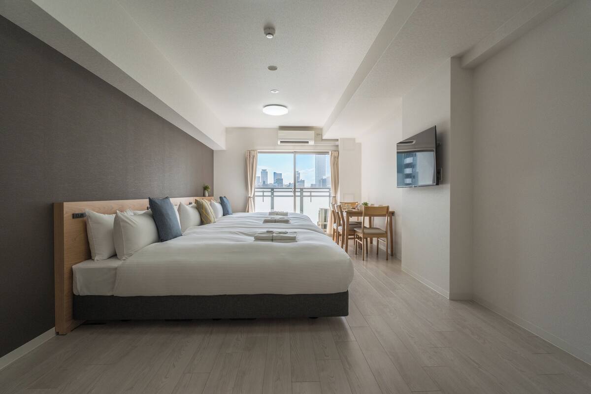Moderni hotellihuone, jossa on suuri sänky, ruokailutila ja näkymä kaupunkiin.