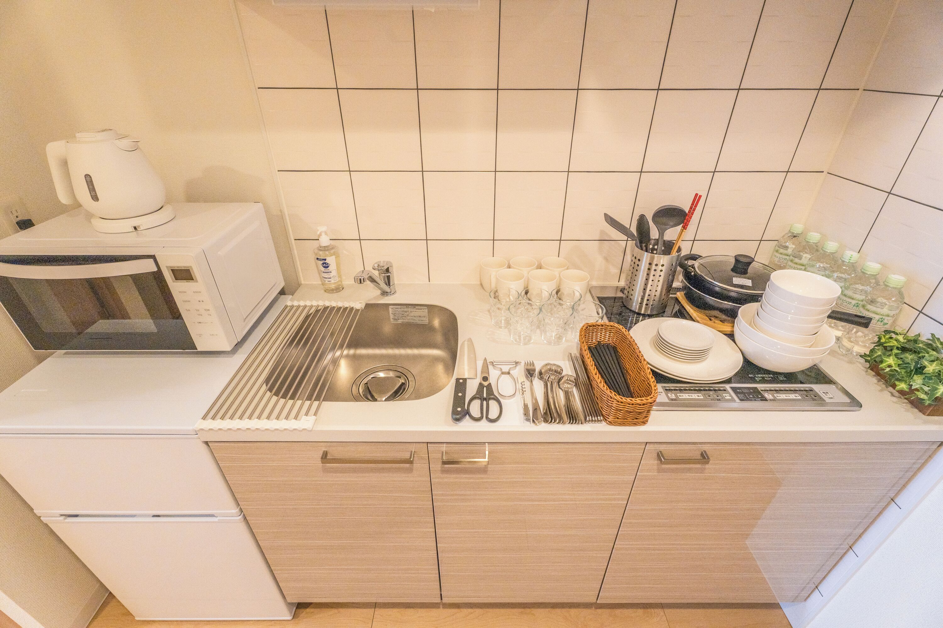 Uma cozinha moderna equipada com micro-ondas, pia e diversos utensílios e louças.