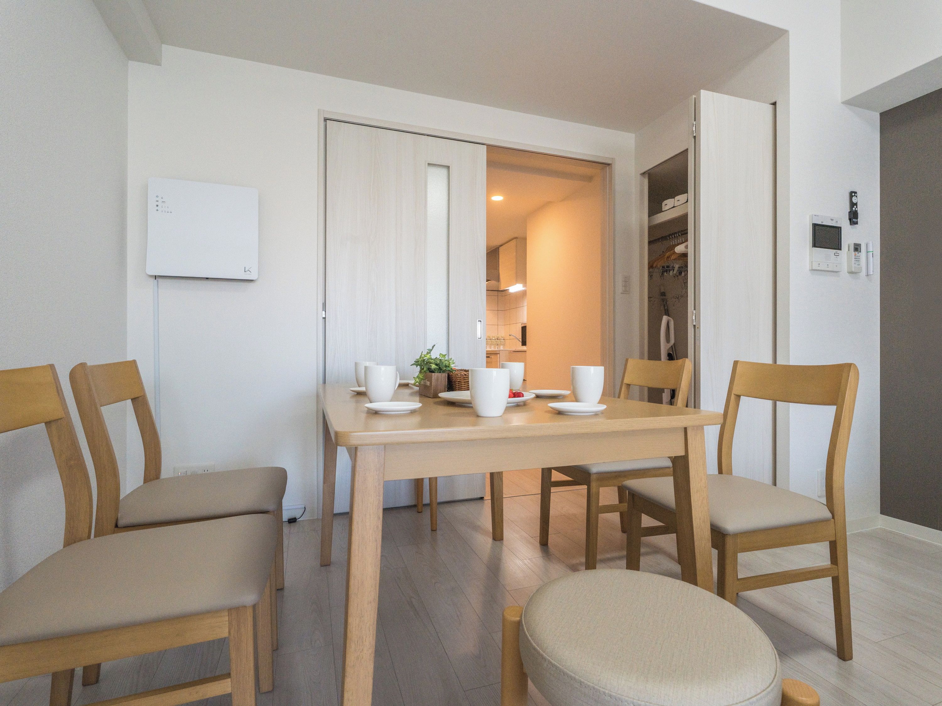 A dining area with a table, chairs, and a kitchen in the background.