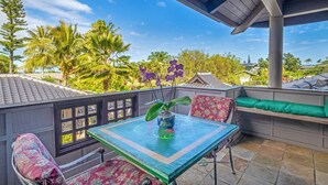 Un balcon avec une table, des chaises et un pot de fleurs.