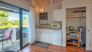 Une cuisine compacte équipée d’un four à micro-ondes, d’une machine à café et d’une étagère contenant des ustensiles de cuisine.