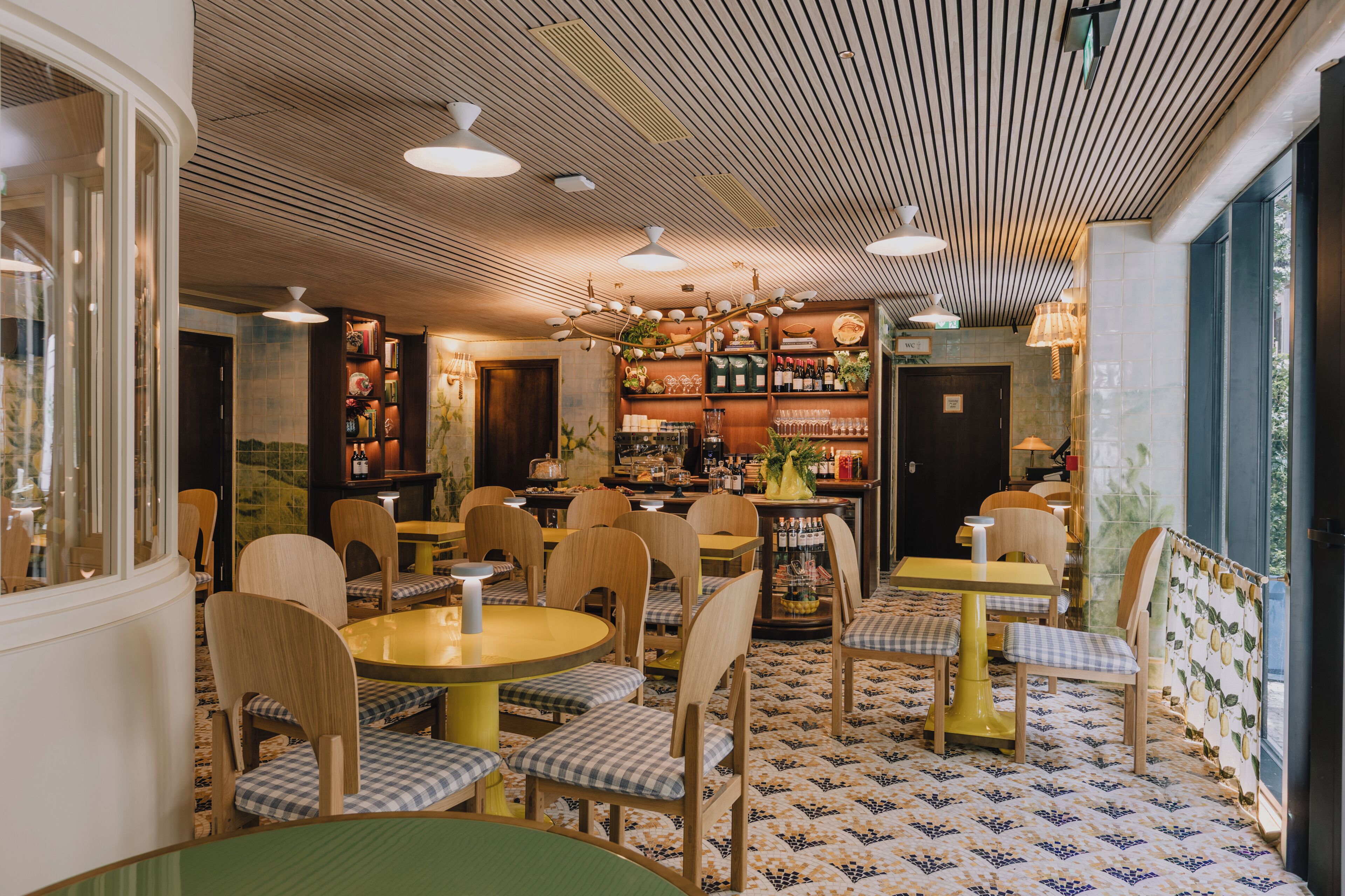 Interior de restaurante con sillas de madera, mesas redondas y un piso con diseño.