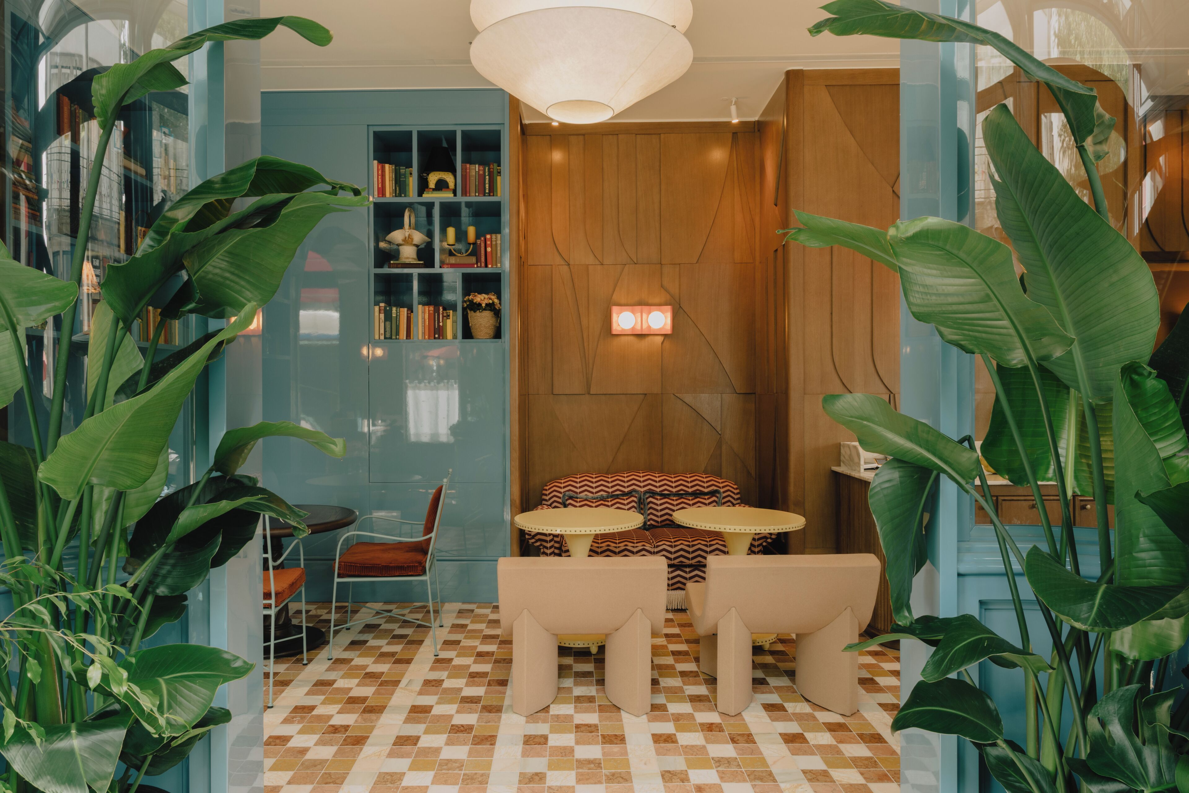 A room with a checkered floor, a wooden wall, a bookshelf, and a table with chairs.