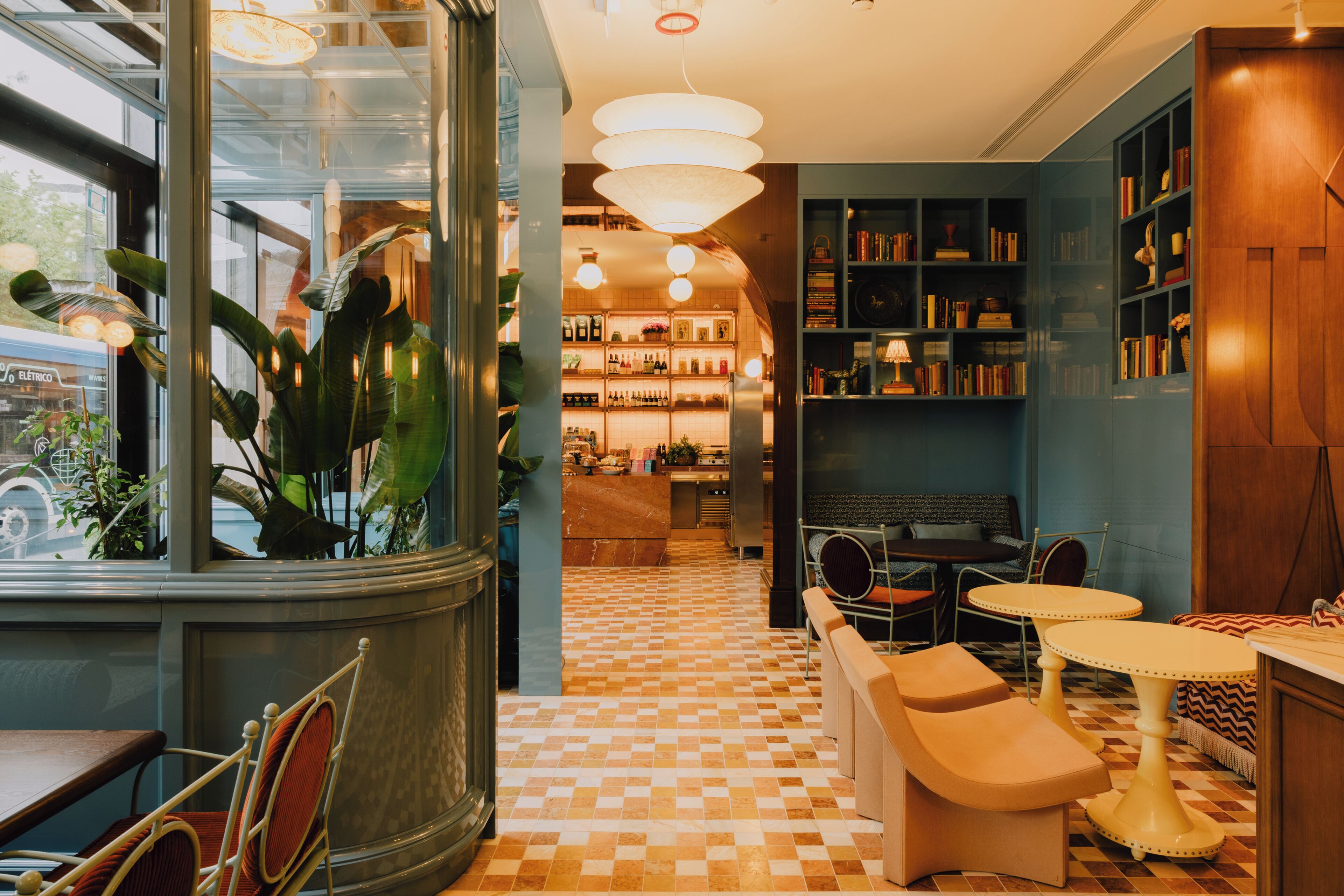 A hotel lobby with a checkered floor, seating areas, and a bookshelf.