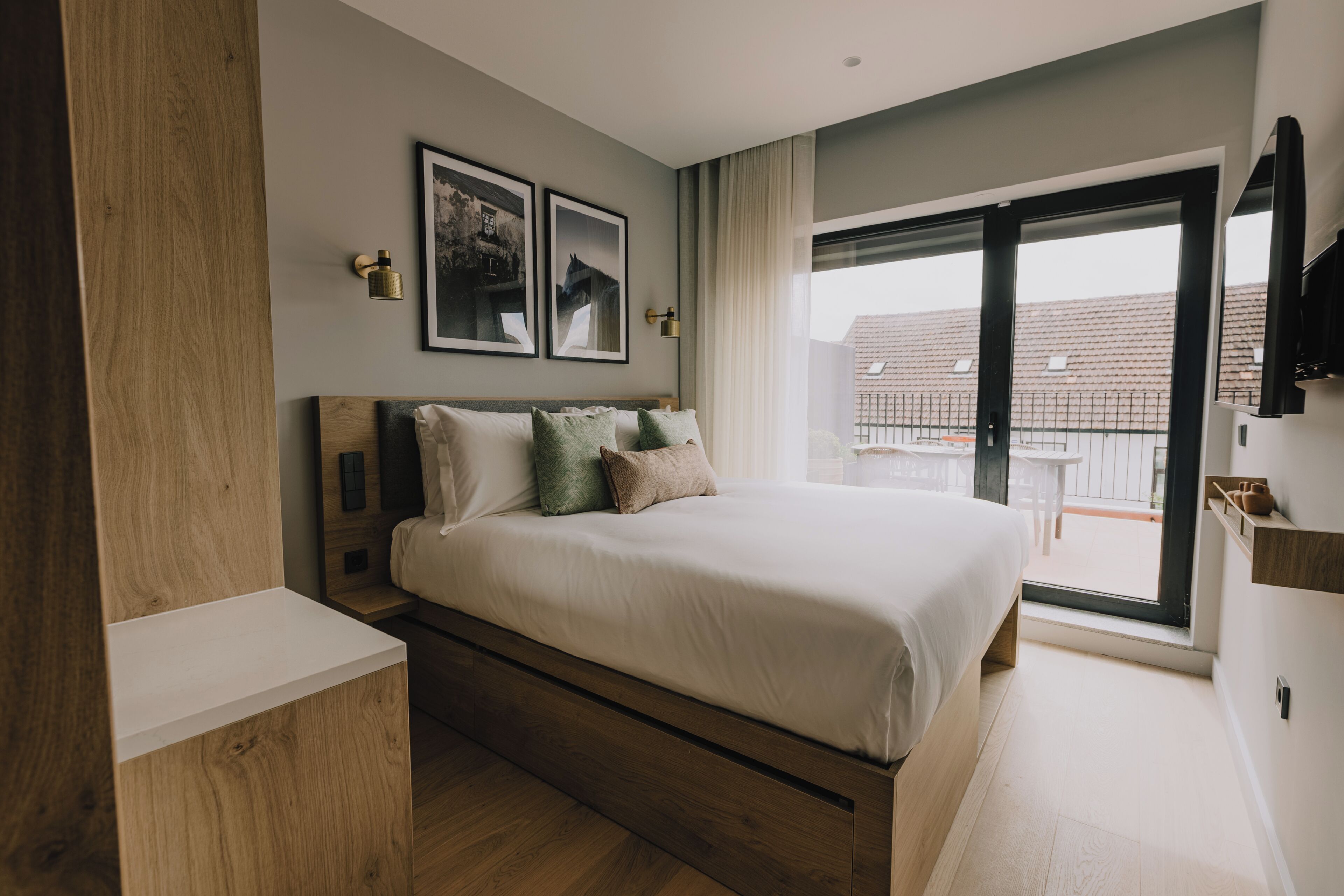A modern bedroom with a large bed, wooden headboard, and a sliding glass door leading to an outdoor area.