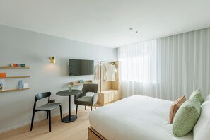 A modern hotel room with a bed, a desk, a chair, a TV, and a window with curtains. - Wilde Aparthotels Porto, Clérigos (Porto)