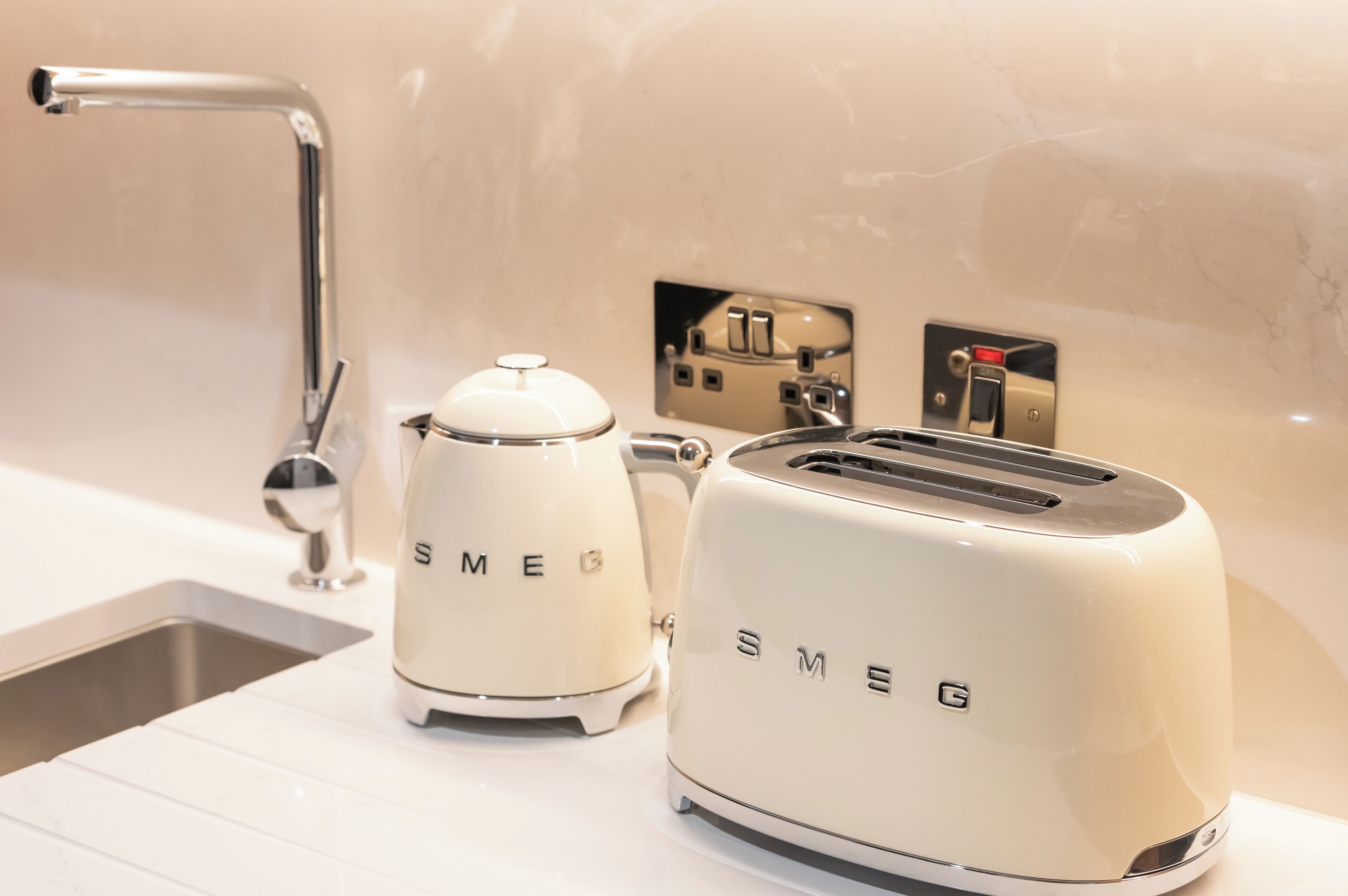 Una cocina con un lavamanos moderno, un tostador y una cafetera.