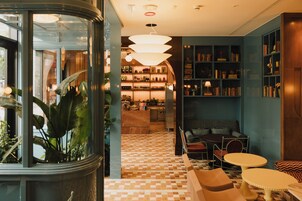Un hall d’hôtel avec un sol à carreaux, un espace salon et une bibliothèque.