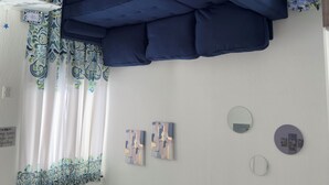 Ein Zimmer mit Etagenbett, gemusterten Vorhängen und Wandbildern.
