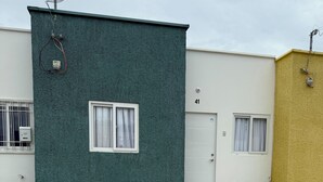 Ein Gebäude mit grüner Fassade, einer weißen Tür und einem Fenster mit weißen Vorhängen.