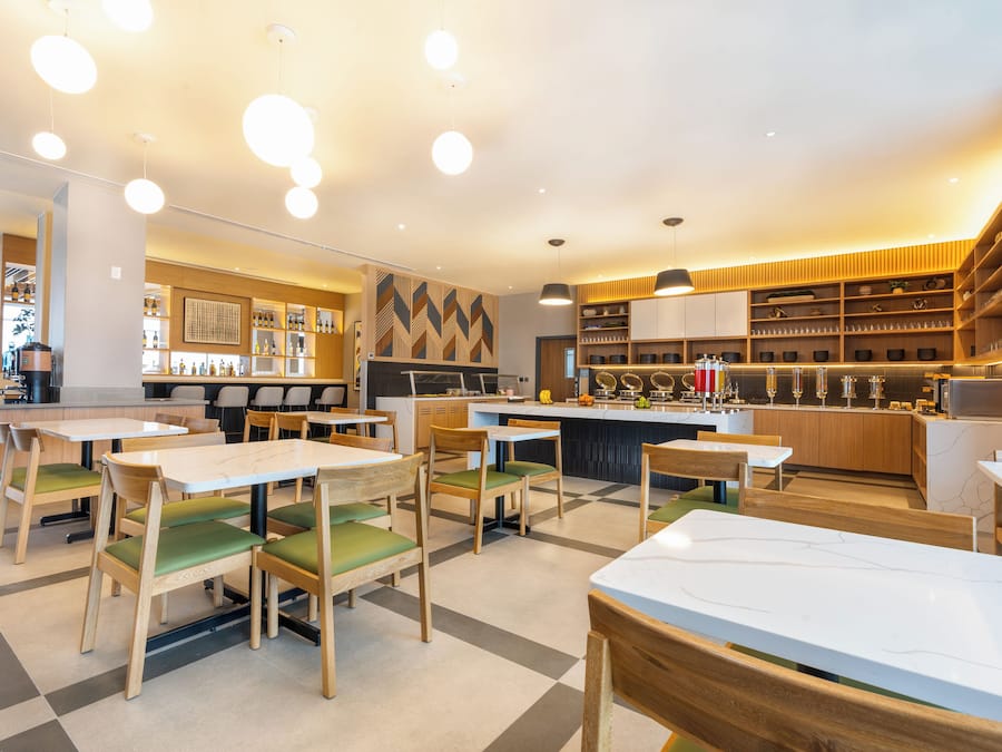 A modern restaurant interior with wooden tables and chairs, a bar area, and a variety of kitchen equipment.