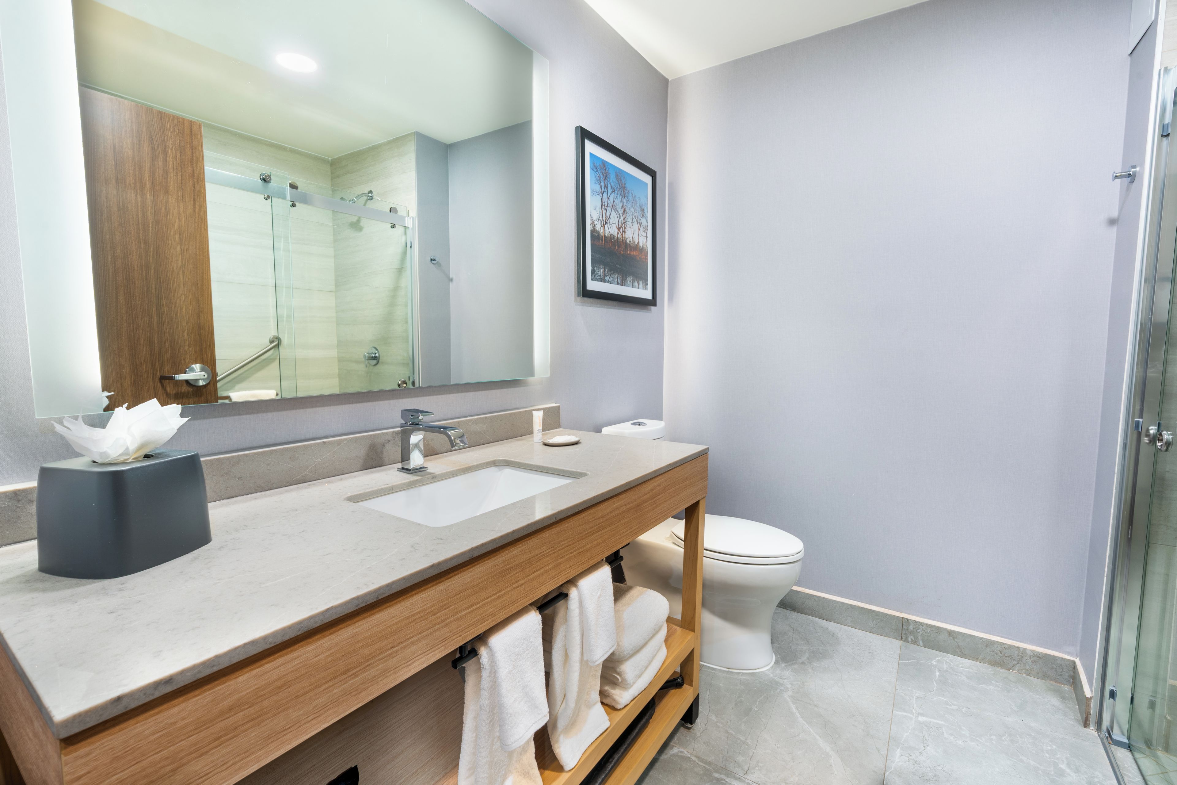 Een moderne badkamer met een grote spiegel, een wastafel, toilet en douchecabine.