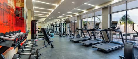 Un gimnasio con cintas de correr, máquinas de pesas y mancuernas.
