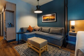 Una sala moderna con un sofá modular, una mesa de centro, una alfombra, un cuadro en la pared y una mesita de noche con una lámpara.