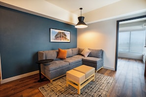 A modern living room with a sectional sofa, a small side table, a wooden coffee table, a patterned rug, and a framed picture on the wall. - Hyatt Place Piedras Negras (Piedras Negras)