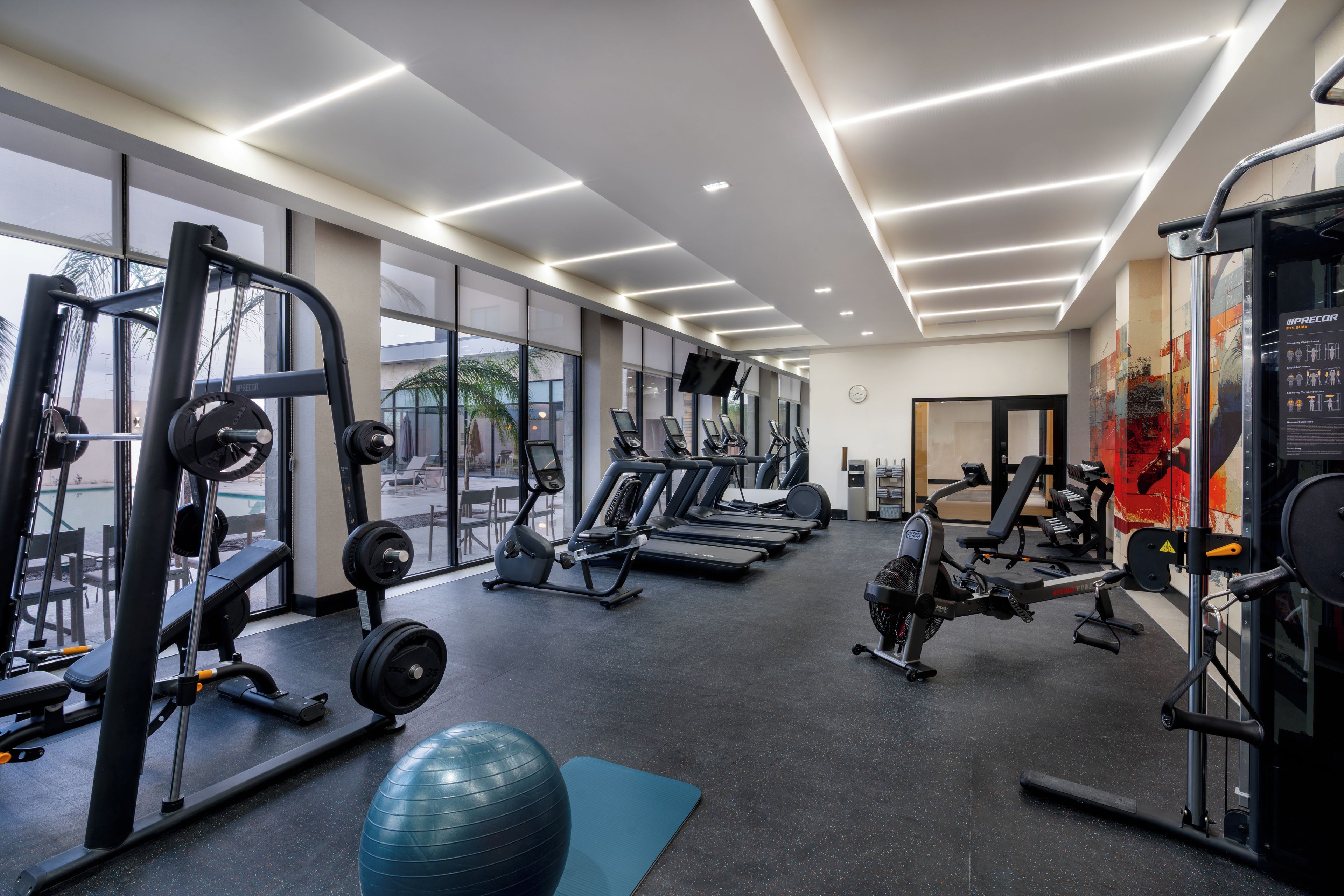 A gym with cardio machines, weightlifting equipment, and a blue exercise ball.