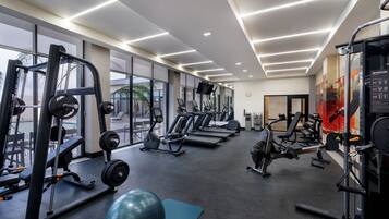 A gym with cardio machines, weightlifting equipment, and a blue exercise ball.
