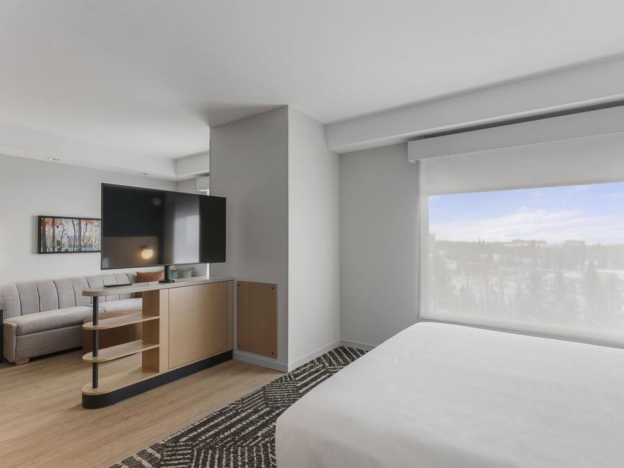 Una habitación de hotel moderna con cama, televisor, sofá y escritorio.