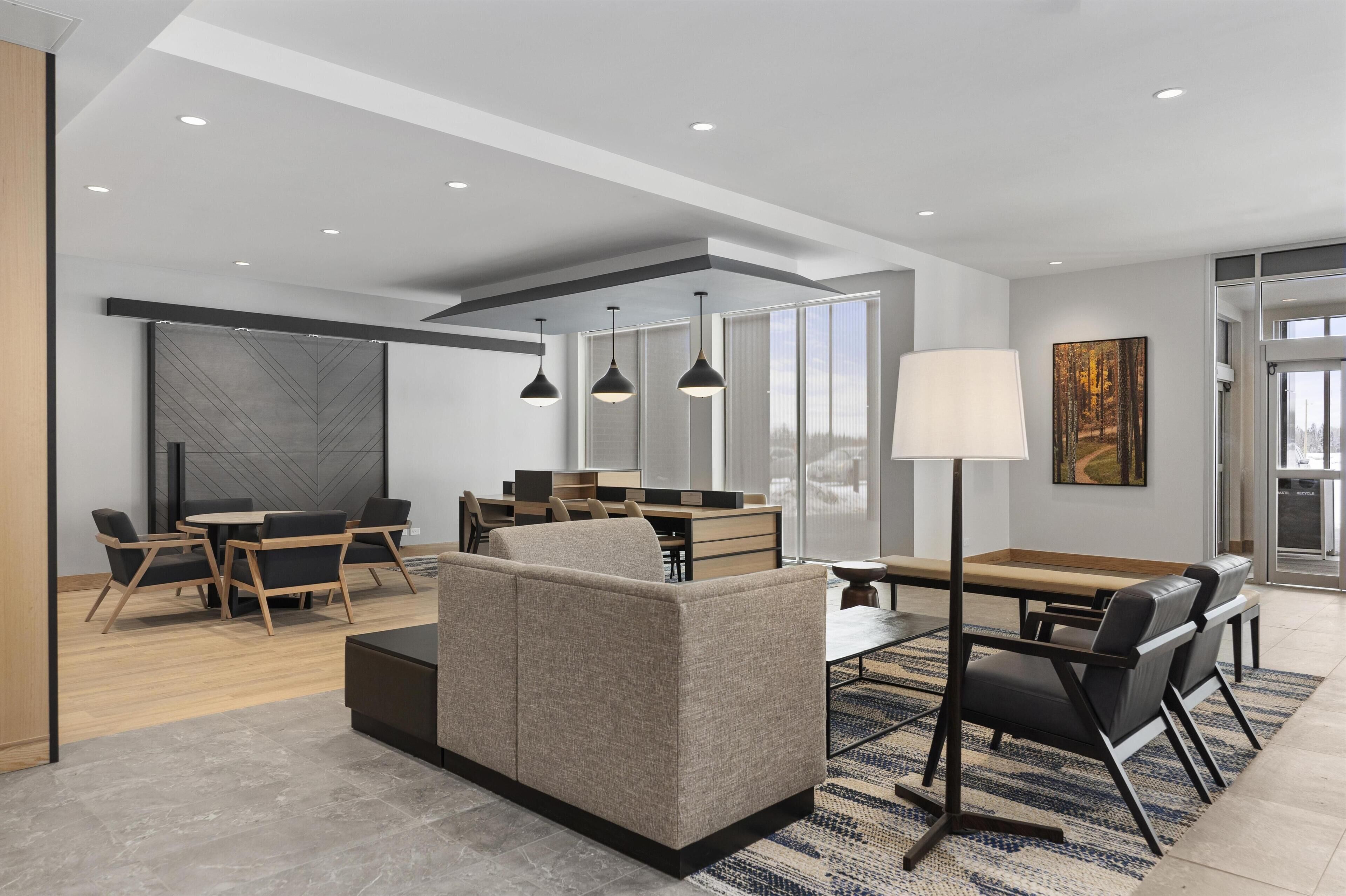 A modern interior with a sofa, dining table, chairs, and pendant lighting.