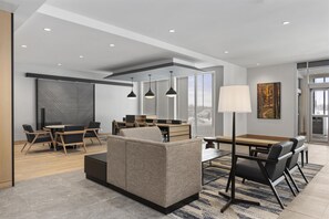 A modern interior with a sofa, dining table, chairs, and pendant lighting.
