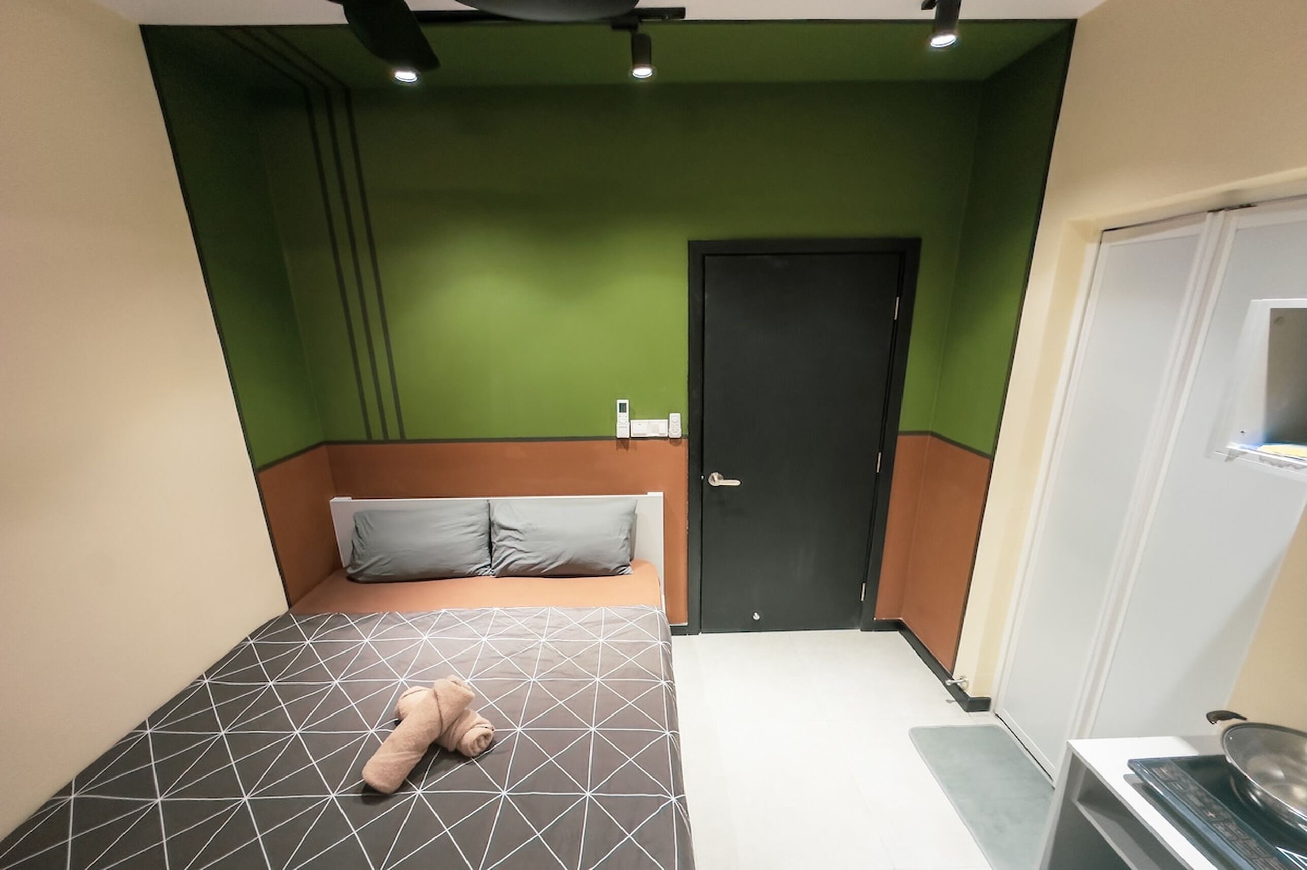 Een kleine, moderne slaapkamer met een bed, een deur en een kitchenette.