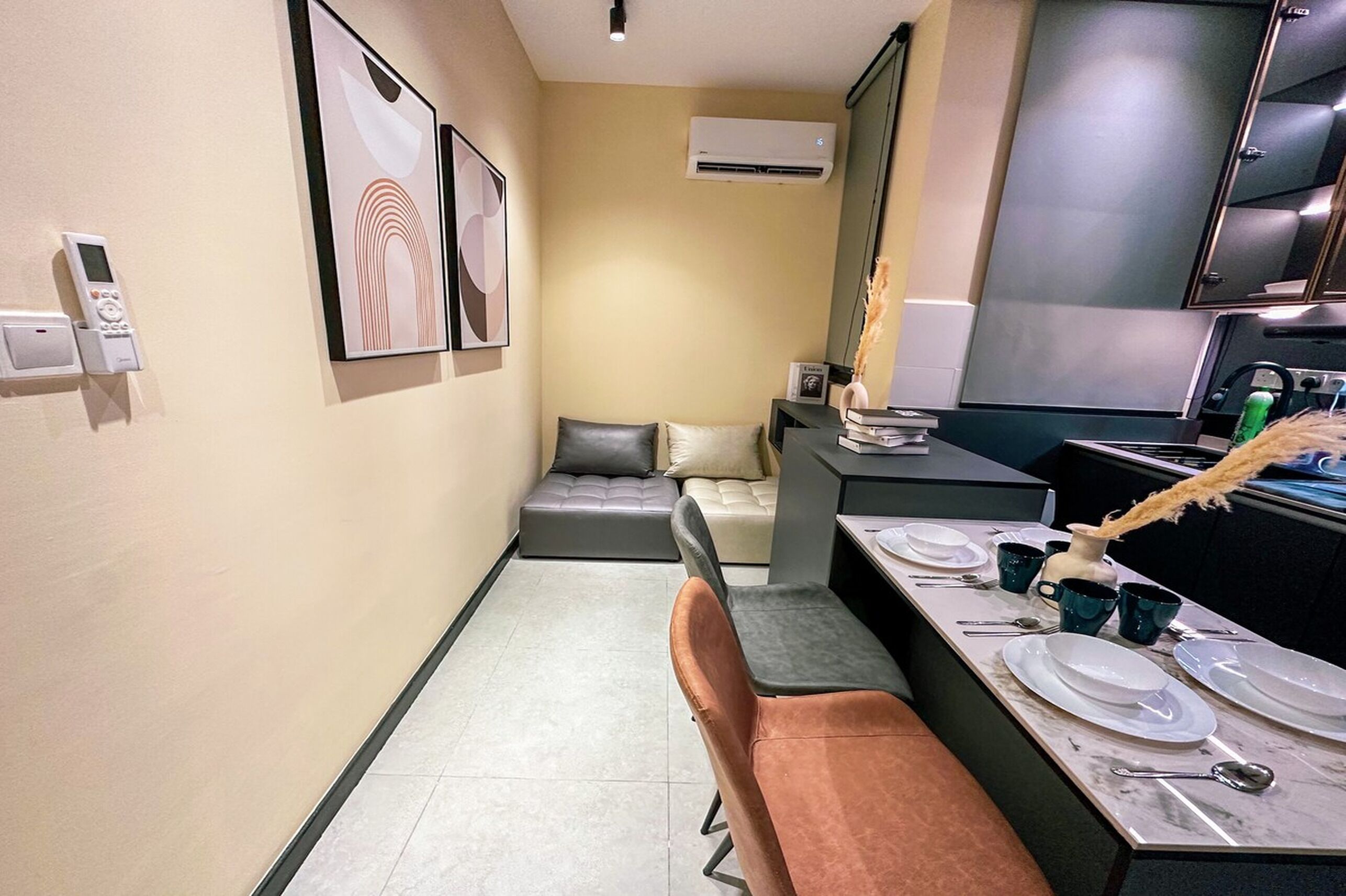A compact hotel room with a kitchenette, a sofa bed, and a dining area with a table set for two.