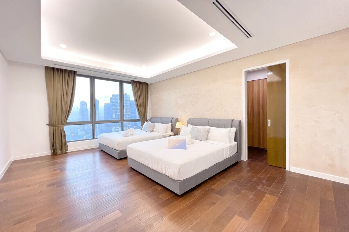 A modern hotel room with two beds, a city view, and a wooden floor.