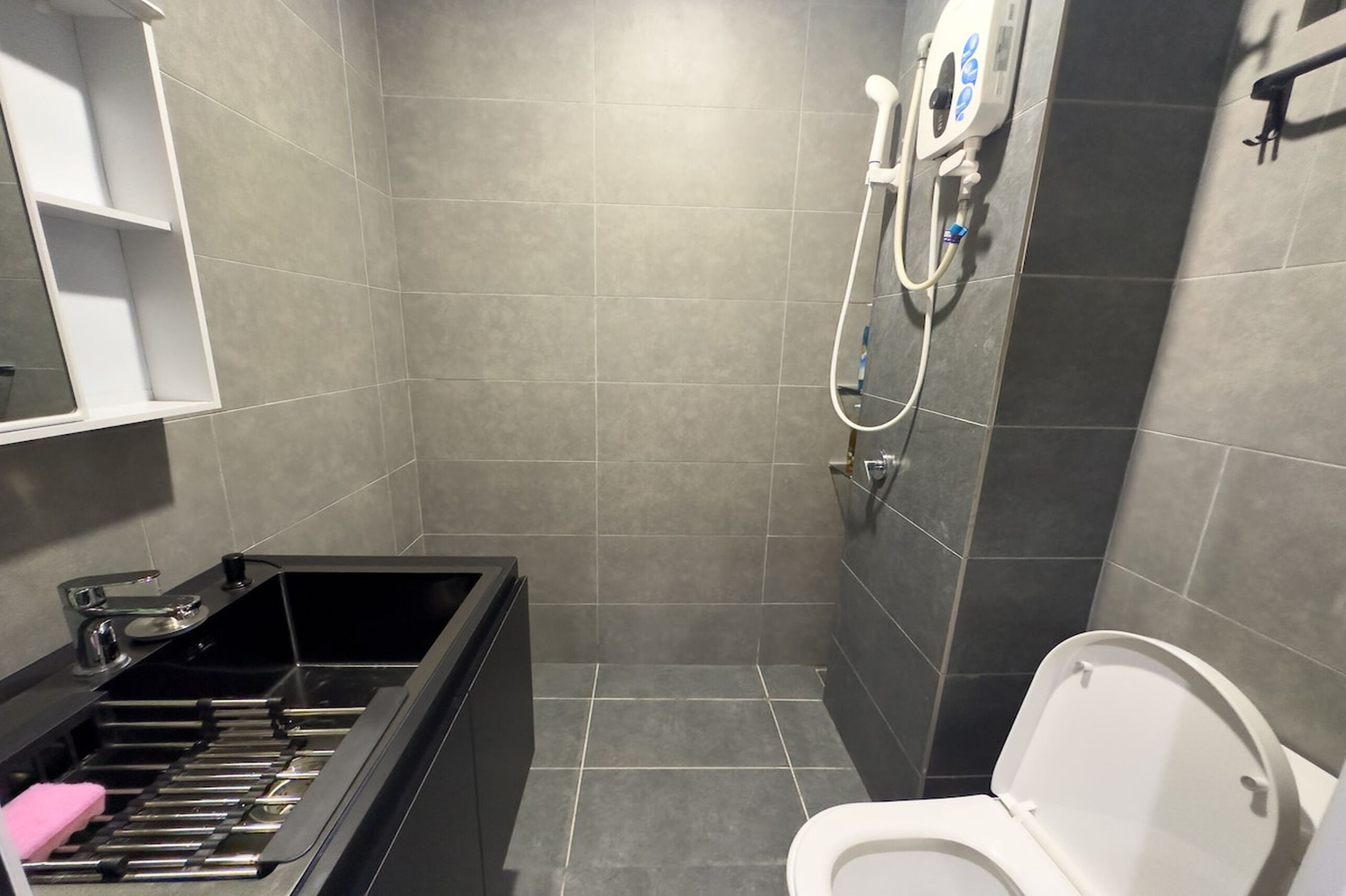 A modern bathroom with a shower, toilet, and a black bathtub.
