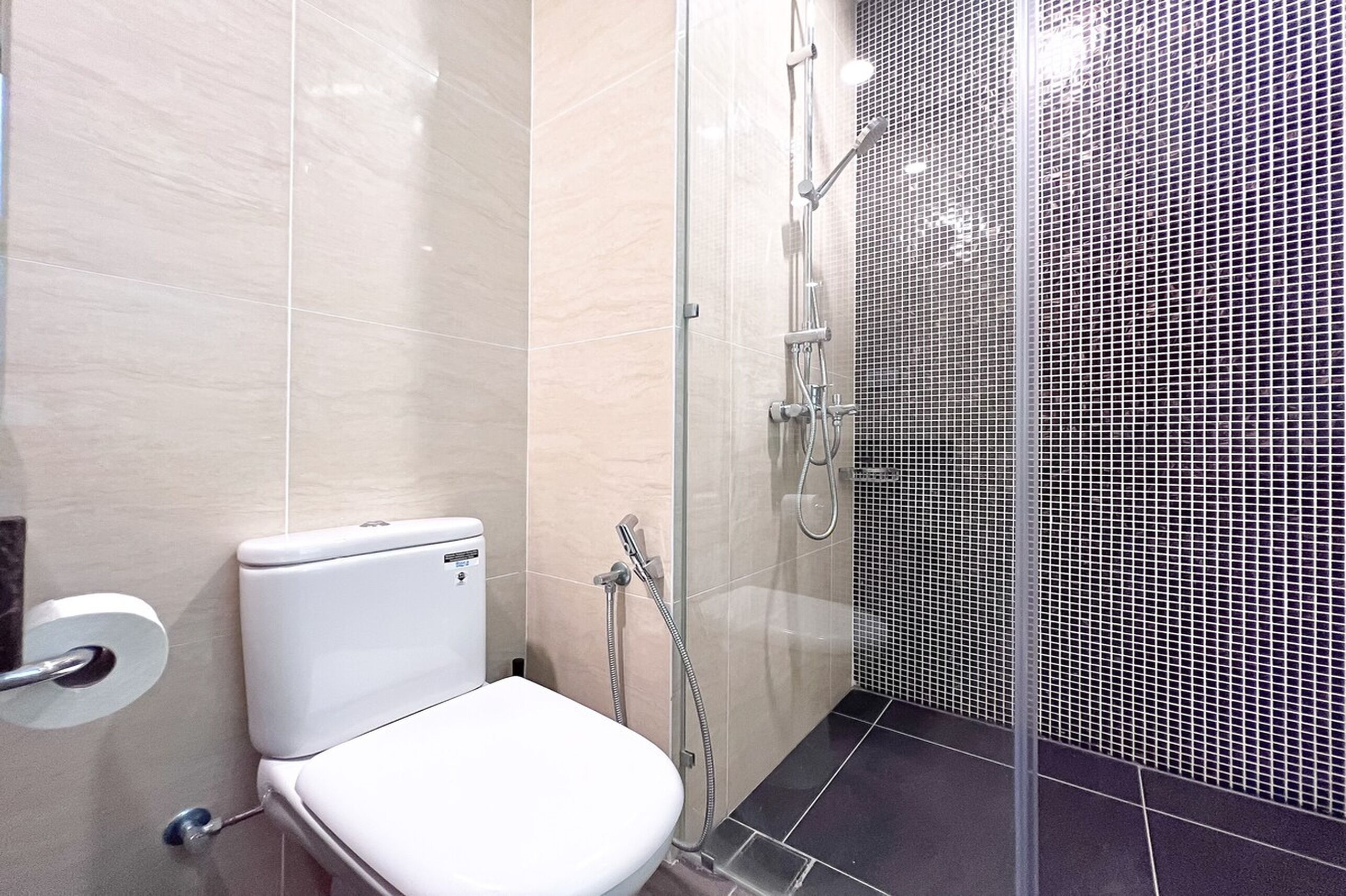 Ein modernes Badezimmer mit Toilette, Duschkabine und Fliesenwänden.