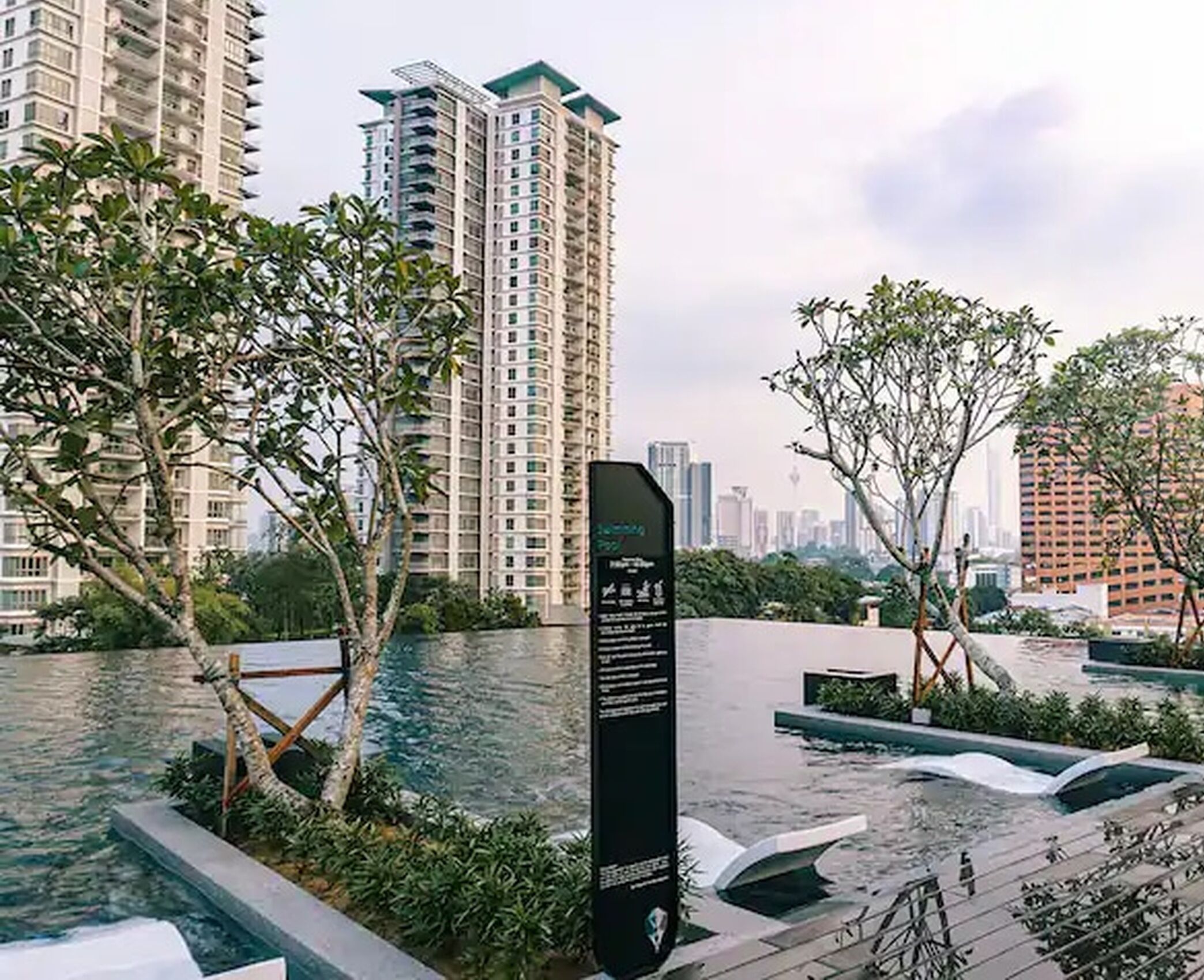 A modern building with a rooftop pool and surrounding greenery.
