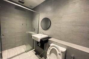 Un baño moderno con cabina de ducha de vidrio, un lavabo blanco y un inodoro.