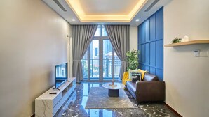 A modern living room with a sofa, coffee table, and a TV on a white console. - Royce Residence KLCC Skyview Apartments (Kuala Lumpur)