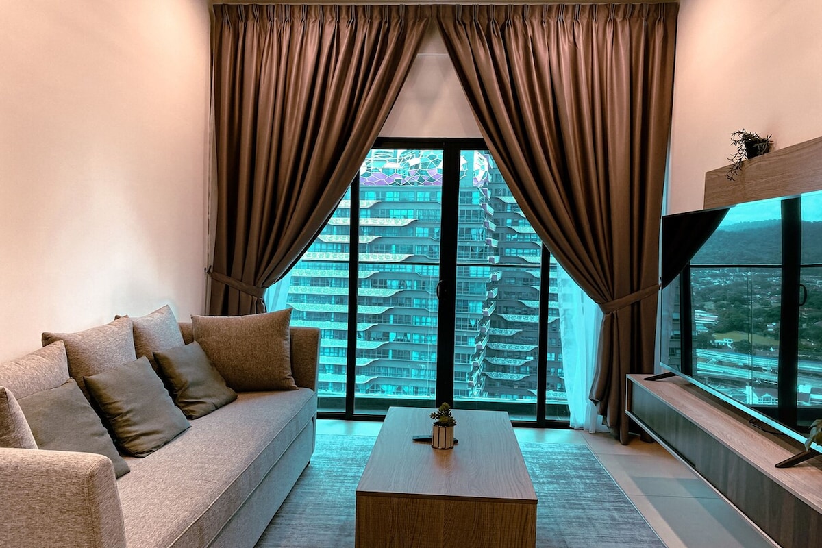 A modern living room with a sofa, coffee table, and large windows with curtains.