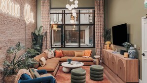 A cozy living room with a brick wall, a large window, and a modern sofa. - Starr Piano: Roxie Suite –  Walk to Broadway! (Nashville)
