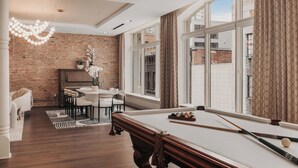 Una habitación moderna con mesa de billar, comedor y ventanas grandes.