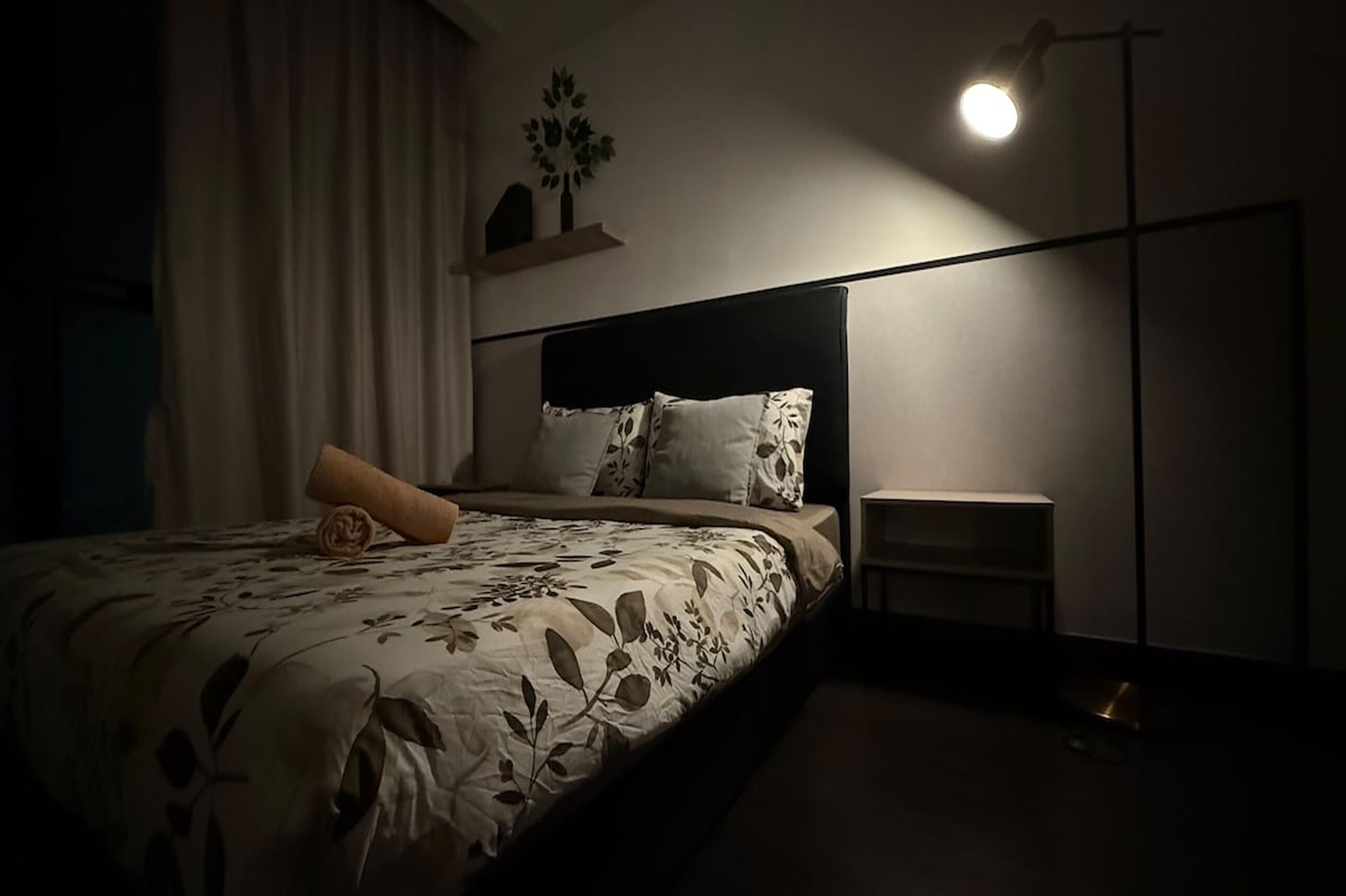 A bedroom with a bed, a bedside table, and a nightstand.