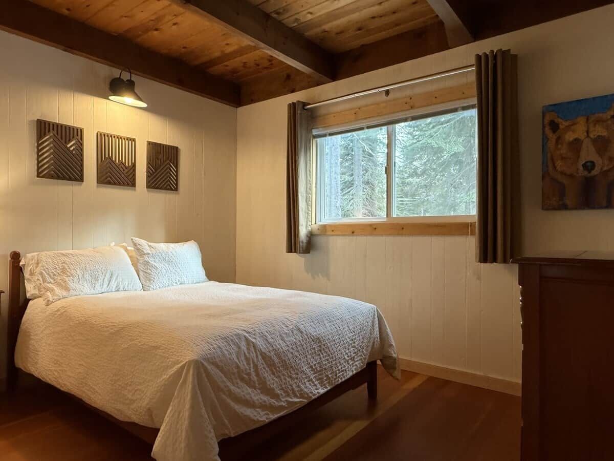 Une chambre à coucher avec un lit en bois, une fenêtre avec des rideaux et des éléments de décoration fixés au mur.
