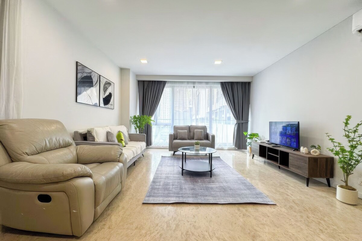 A modern living room with a beige sofa, a smaller sofa, a coffee table, and a TV on a wooden stand.