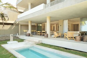 Un espace piscine extérieur moderne, doté d’un coin salon intégré et d’un patio couvert.