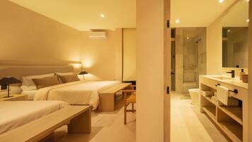 A modern hotel room with two beds, a bench, a desk, a bathroom with a shower, and a large mirror.