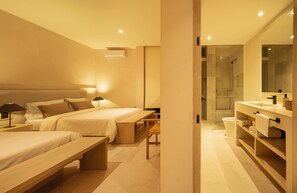 Une chambre d’hôtel moderne avec deux lits, un banc, un bureau, une salle de bain avec douche et un grand miroir.