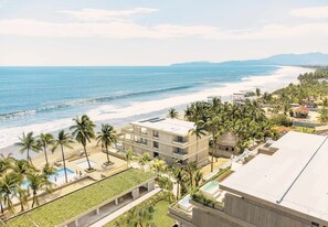 Un complexe hôtelier comprenant plusieurs bâtiments, un espace piscine et offrant une vue sur la plage.
