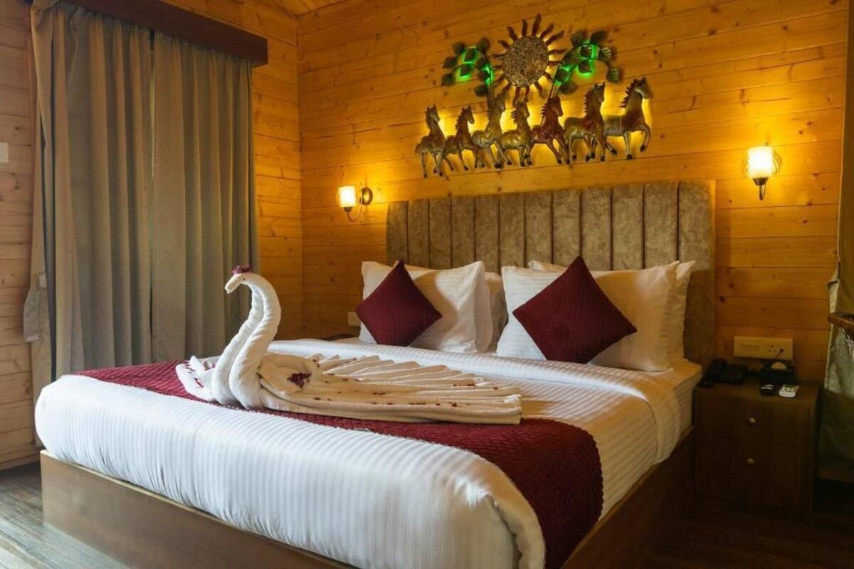 A wooden-paneled room with a bed, two wall-mounted lamps, and a decorative wall piece above the bed.